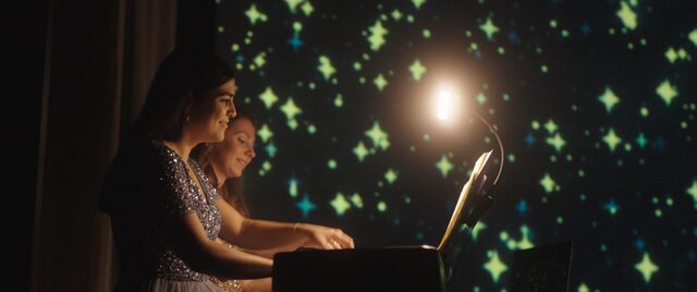 Die Pianistinnen vor einer Leinwand voller leuchtender Sterne